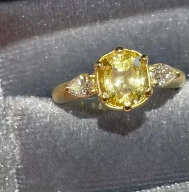 Untreated natural intense yellow sapphire weighing 2.18 ct accented with 2 pear shape white diamonds all set in 18k yellow gold